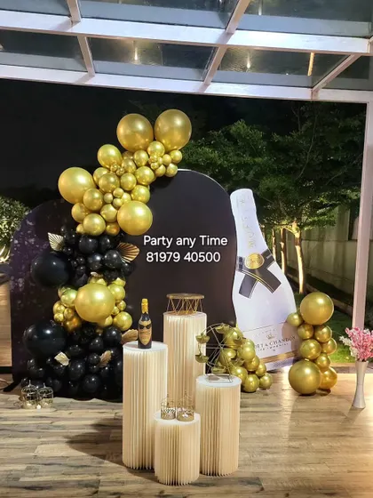 A fun and glamorous champagne-themed decoration with a giant bottle cutout and black and gold balloons.