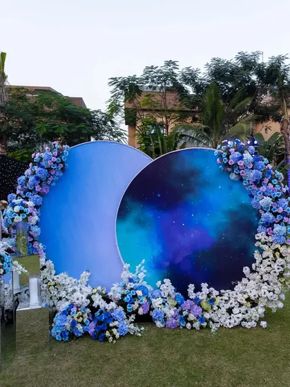 A creative photo-op with two large circular backdrops painted to look like a moon and a galaxy. Framed with blue and white hydrangeas, it was a popular spot for photos.