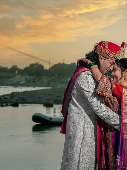 An embrace that feels like coming home. A romantic shot of the couple by the river, with the sunset painting the sky.