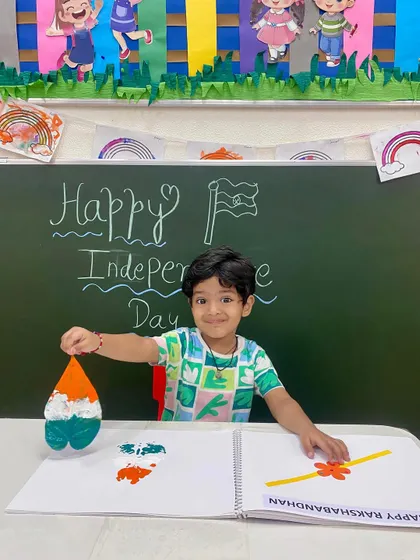 A proud smile and a beautiful creation. This student shows off his leaf-printed artwork, a perfect example of how we blend learning about national holidays with fun, creative expression.