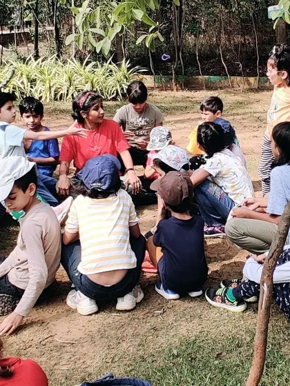 A group gathers in the park for an outdoor lesson with an expert, learning about the small wildlife found in the soil.