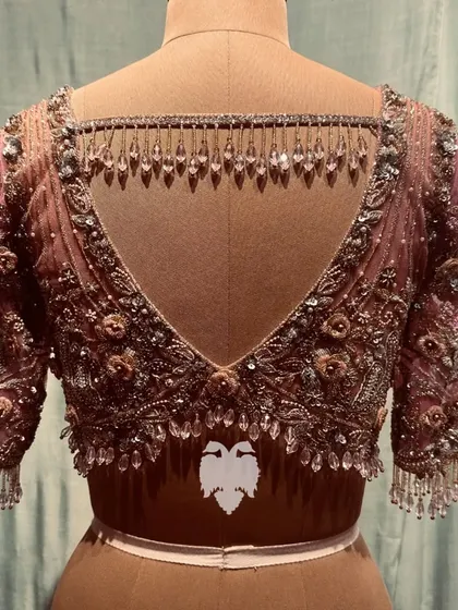A pastel pink blouse for Sireesha's reception, where silk and net amalgamate with 3D flowers for a mystical, fairy-tale aura.