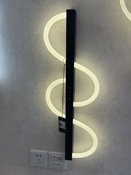 A modern, serpentine LED wall light. This fixture creates a dynamic, flowing line of light on the wall, perfect for a contemporary space.