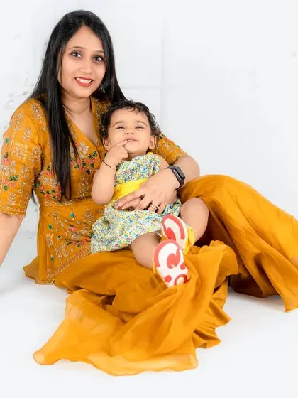 A mother and daughter in beautiful matching yellow outfits share a happy moment. The photo is bright, cheerful, and full of love.