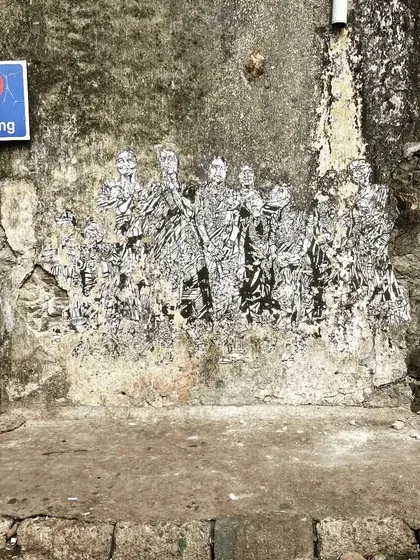 A fading paste-up artwork on a weathered wall at Sassoon Dock. This image captures the temporary and evolving nature of street art, which changes and decays over time.