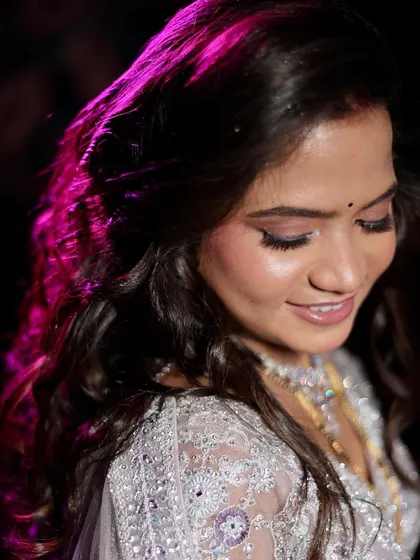 A close-up of the bride's soft and shimmery makeup. The pink lighting adds a touch of magic to the look.