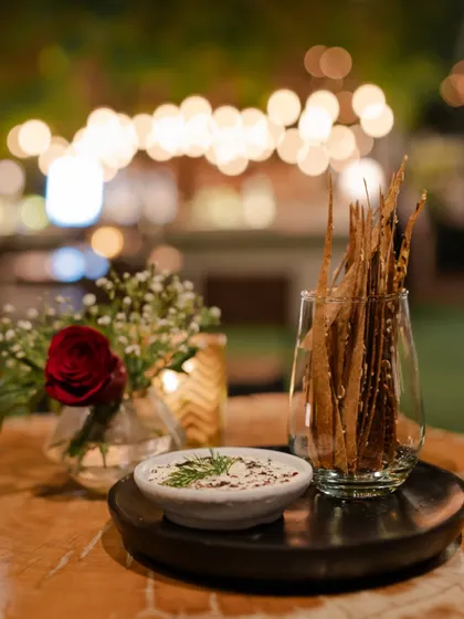 A simple and elegant snack setup on a table, featuring hummus and crispy lavash sticks.