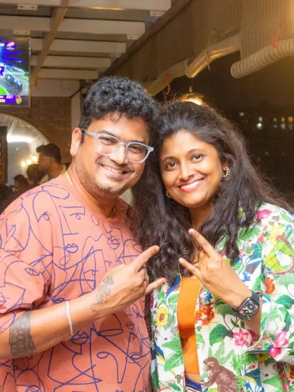 A couple enjoying the vibrant atmosphere at the pub. The live cricket match playing on the screen behind them adds to the energetic vibe of the evening.