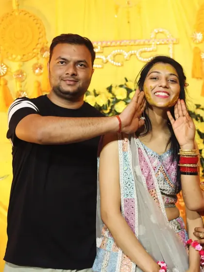 Documenting the core rituals of the Haldi ceremony is essential. This photo shows a guest lovingly applying turmeric paste to the bride-to-be's cheek, a classic and happy moment.