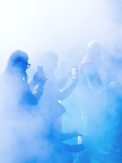 Audience members capture the "To Da Bone" performance on their phones through a haze of stage smoke. This image shows the immersive and visually stunning nature of the show.