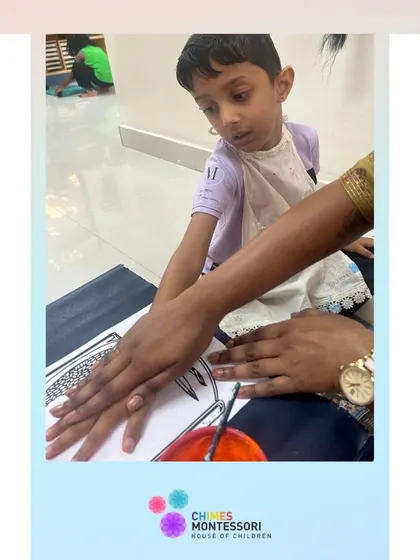An adult helps a child make a handprint, guiding him gently in the creative process.