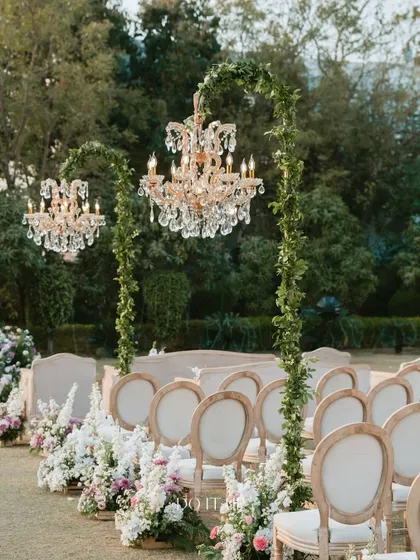 The guest seating for this outdoor Jaipur wedding featured elegant chairs and chandeliers on stands wrapped in greenery. This detail elevated the entire space, making it feel like a grand, open-air ballroom.