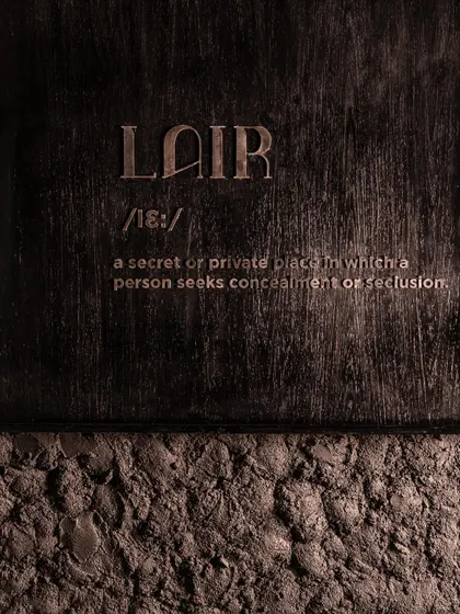 The definition of "Lair" etched into the wall, a direct statement of the brand's identity.