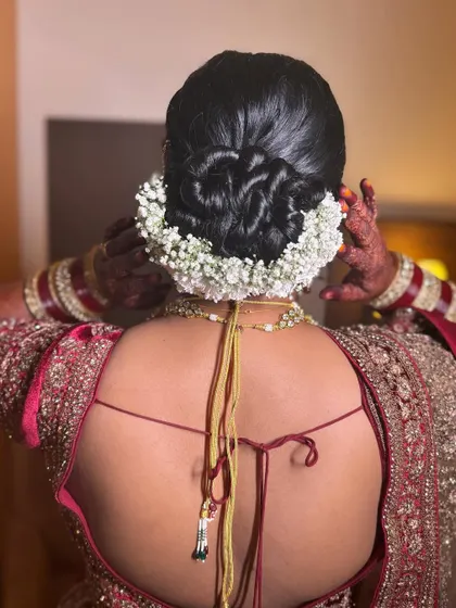 A classic twisted bun fully encircled by a fresh white gajra. This is a go-to style for the main wedding ceremony, as it's both secure and traditionally beautiful.