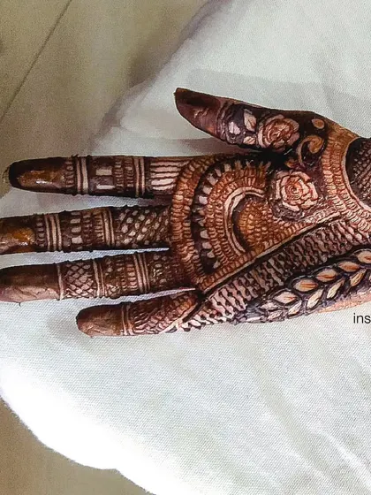 A detailed view of the finger and palm work in a traditional design. Each finger has a unique pattern, and the palm features delicate floral and leaf motifs.
