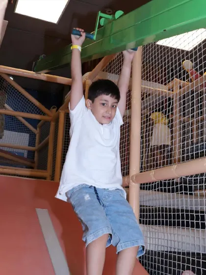 A boy hangs from the monkey bars, building strength while having fun.