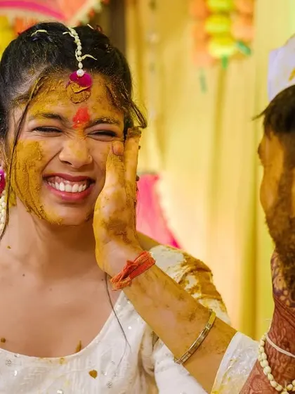 A candid shot of the groom playfully applying haldi to the bride's face, capturing her joyful reaction.