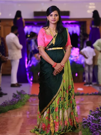 A client looking elegant at an event in a custom-styled half saree. The floral print skirt is paired with a dark green dupatta and a bright pink blouse.