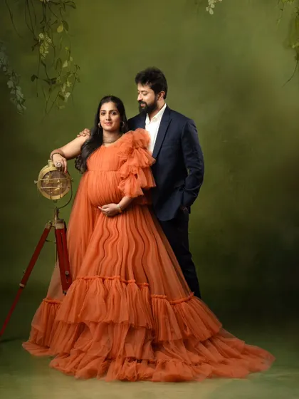 A sophisticated couple's portrait, with the partner in a suit complementing the vibrant orange gown.