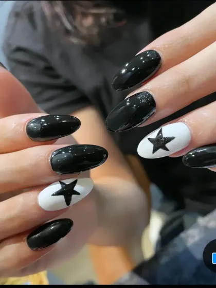 A bold, high-contrast design with glossy black nails and accent nails featuring a black star on a white base.
