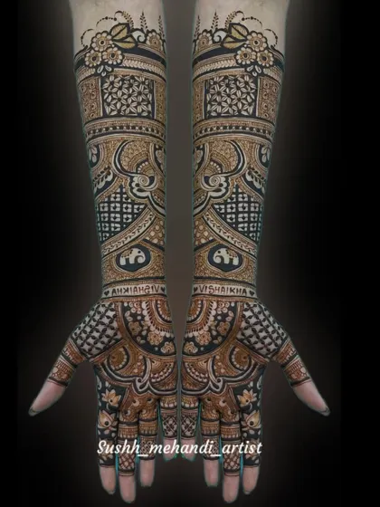 A full view of a complex bridal design against a black background, which makes the details pop. The names of the bride and groom are hidden within the patterns.