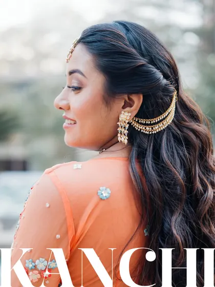 A beautiful profile shot of the bride, Kanchi, showcasing her elegant hairstyle and stunning traditional earrings during her Haldi ceremony.