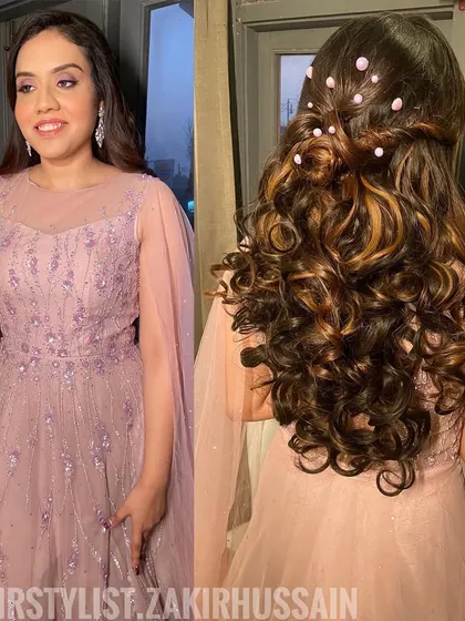 A glamorous half-updo with voluminous curls and pearl accents, perfect for a reception or engagement party. The highlights in the hair add beautiful dimension.