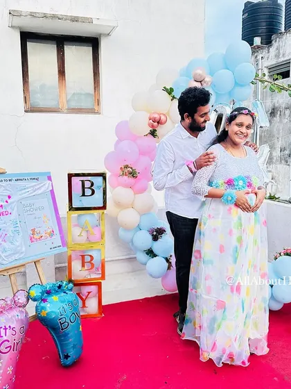 A beautiful moment between the parents-to-be at their terrace baby shower. The pastel pink and blue balloon decor creates a soft and joyful backdrop for their celebration.