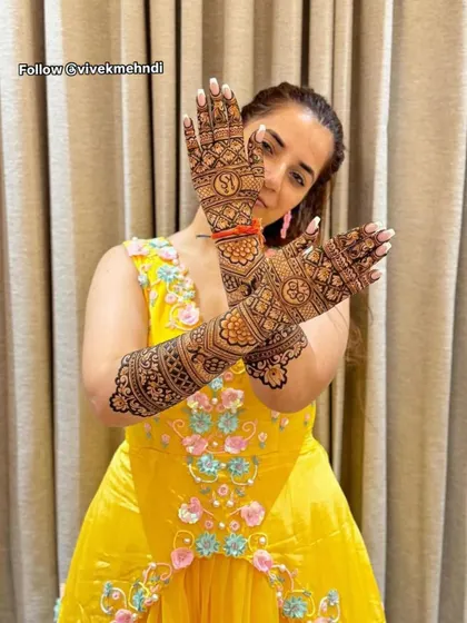 A client showing off her stunning mehndi with personalized initials. The intricate jaal pattern covers the entire hand, creating a very rich look.
