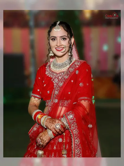 A half-length portrait of the bride in her red wedding lehenga. This shot offers a clear view of her complete look, from the traditional nath to the intricate embroidery on her outfit.