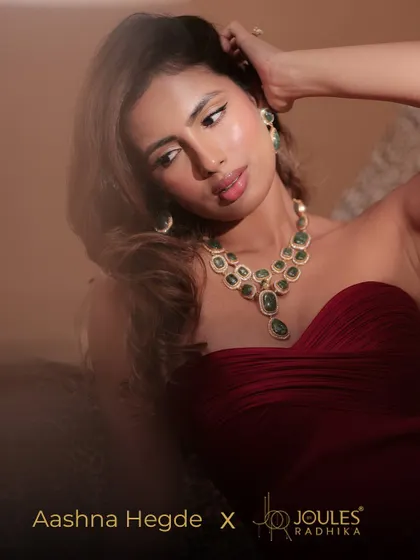 A beautiful portrait of Aashna Hegde, her confident gaze directed at the camera, showcasing the beauty of the emerald green necklace.