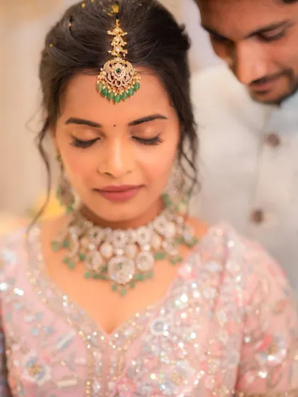 A beautiful close-up from an engagement ceremony. The makeup is soft and romantic, with a focus on the eyes, and pairs perfectly with her pastel pink lehenga.