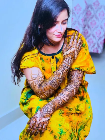 A beautiful shot of the bride showing her full bridal henna on her arms, with a hint of the matching design on her feet.