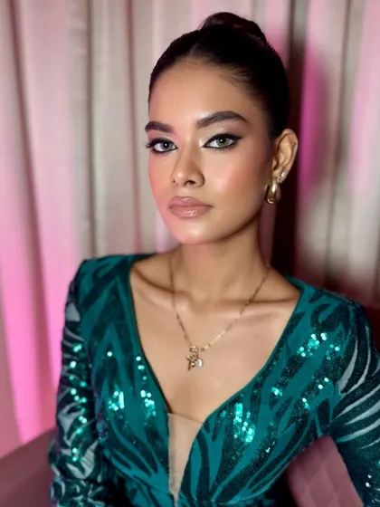A close-up of this fierce and modern look. The sharp winged liner, combined with a sleek updo and a sequined green dress, creates a powerful and glamorous statement.