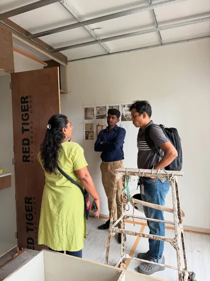 Another angle of the on-site discussion, with the raw plywood structure of the furniture visible.