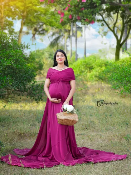 A beautiful solo portrait in a wine-colored gown, set against a lush green background. The long train of the dress adds an elegant touch.