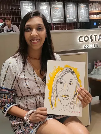 A guest at my Costa Coffee collaboration event, holding her fun caricature.