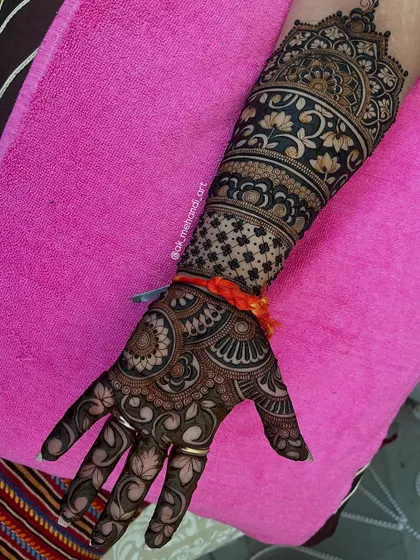 A beautiful bridal arm design featuring a mix of traditional motifs. The orange 'mauli' thread tied on the wrist is often part of pre-wedding rituals.