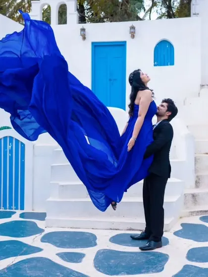 This is all about creating a fun, dynamic shot. I provided this vibrant blue flying gown and styled the couple for a high-energy pre-wedding photoshoot against a Santorini-themed backdrop.