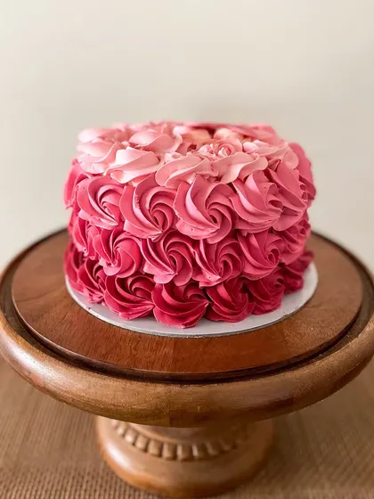 A beautiful cake featuring pink ombre buttercream rosettes. This design is perfect for birthdays and anniversaries, with a little heart plaque that reads "Happy 50th young lady!"