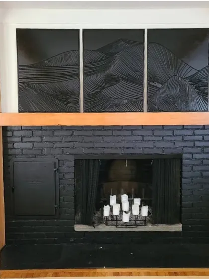 The same three-panel mountain art, shown here in a dramatic black finish. It creates a powerful focal point above this modern black brick fireplace.