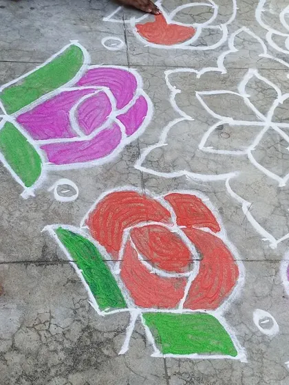 A close-up of the rangoli being filled with bright colors. The children love watching and participating in this traditional art form.
