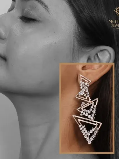 A pair of modern, geometric chandelier earrings. The cascading triangles of diamonds create a sharp, contemporary look that is both edgy and elegant.