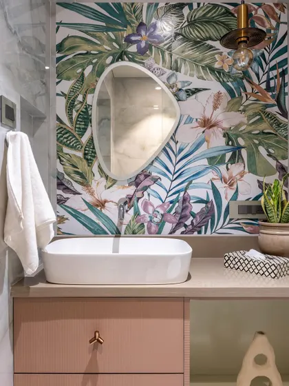 A bathroom that brings the outdoors in. The tropical leaf wallpaper, paired with a simple vessel sink and a pink vanity, creates a fresh and vibrant oasis that feels like a mini-vacation.