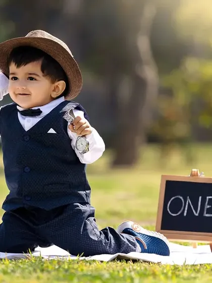 A stylish outdoor portrait of a little boy tipping his hat, holding a vintage-style pocket watch prop for a timeless look.