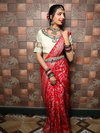 A full-length shot showing the beautiful drape of the red saree. The pose is elegant and showcases the entire outfit from head to toe.