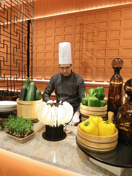 A chef at a prep station, surrounded by fresh, vibrant vegetables. We believe in using only the highest quality ingredients as the foundation for our culinary creations.