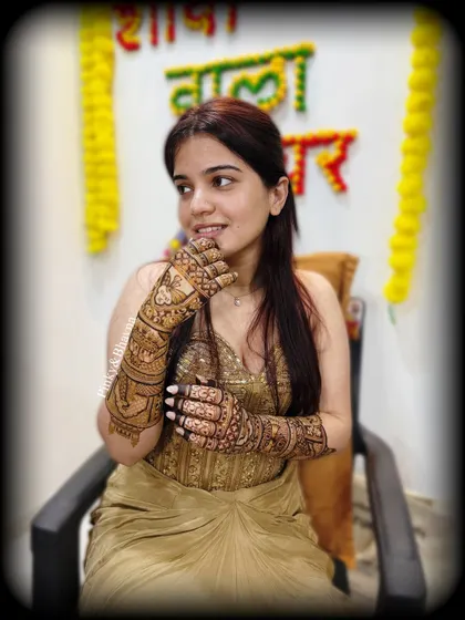 A beautiful candid shot of the bride during her mehndi ceremony, with a "Shaadi wala ghar" sign in the background.