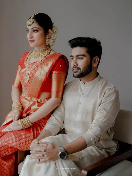 An elegant and poised portrait of the couple in their traditional red and cream wedding attire.