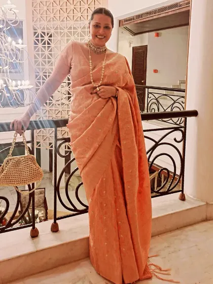 Another view of this elegant peach saree, perfect for a wedding reception or festive gathering. The delicate fabric and soft color are universally flattering.